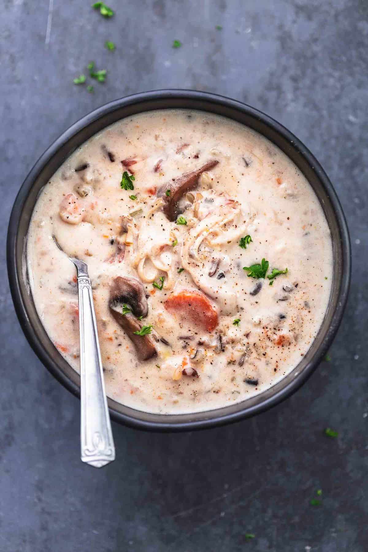 Hühnchen-Wildreissuppe mit Löffel in schwarzer Schüssel