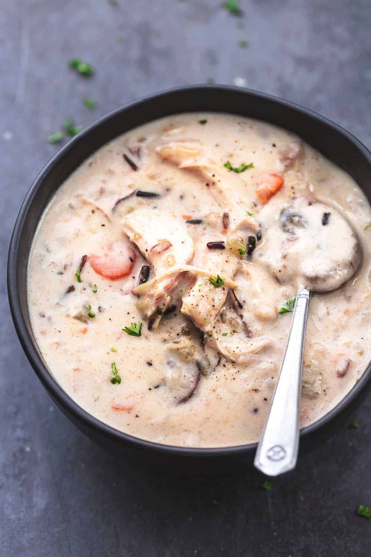 Hühnchen-Wildreissuppe mit Löffel in schwarzer Schüssel