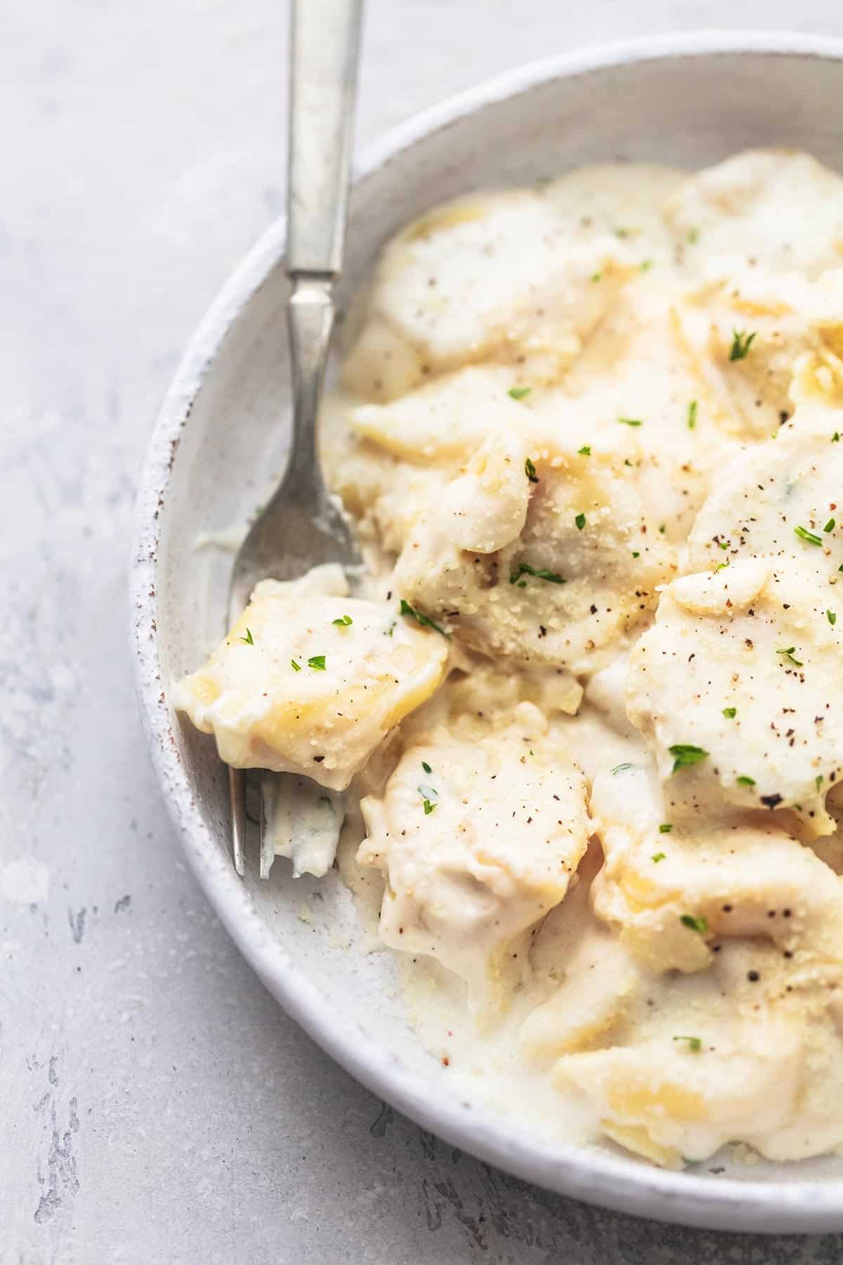 Tortellini-Nudeln aus nächster Nähe mit Alfredo-Sauce mit einer Gabel